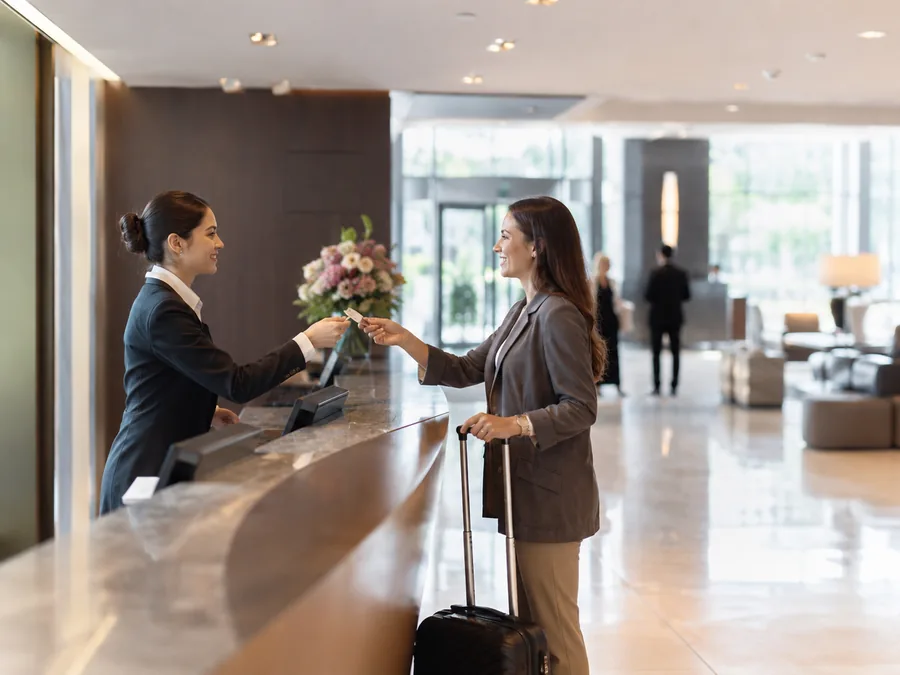 Recepcionista de hotel atendiendo a una clienta en un lobby moderno